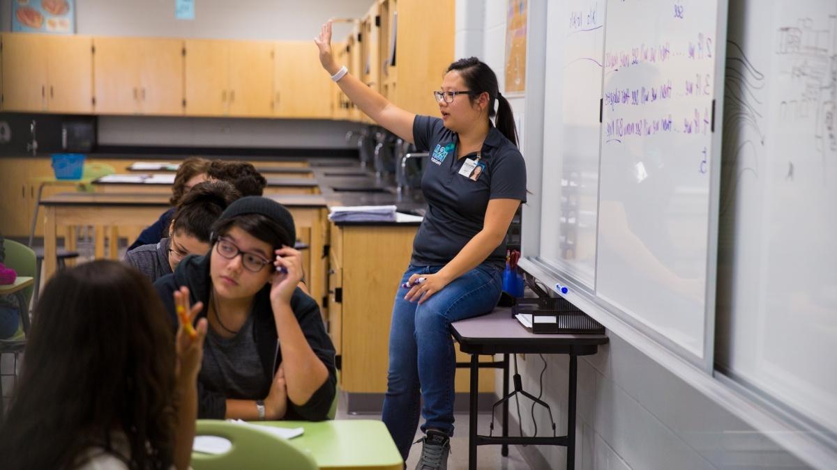 Trinity student teaching a high school classroom, while standing at whiteboard